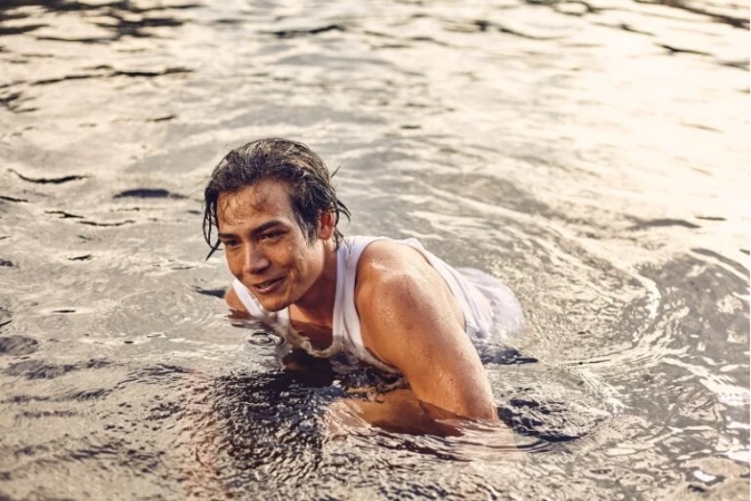 Wet man in white tank top swimming in a natural body of water captured by Coty Tarr