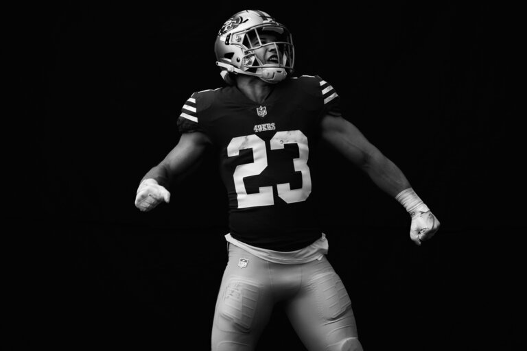Black and white image of a football player in uniform with number 23. The subject is facing the camera in a low-lit tunnel.