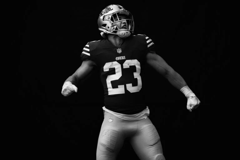 Black and white image of a football player in uniform with number 23. The subject is facing the camera in a low-lit tunnel.