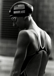 Monochrome portrait of a female swimmer wearing a cap with American flag and Douglass text, shot by Coty Tarr.