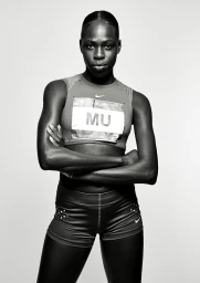 Black female athlete with arms crossed wearing athletic top and shorts against a white seamless background