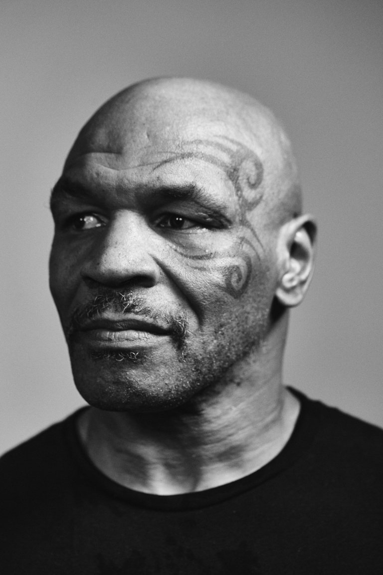Monochrome portrait of Mike Tyson with a distinctive face tattoo. Bald head and serious expression in a close-up studio shot.