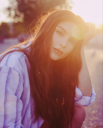 Portrait of a woman with long hair in a striped shirt bathed in golden hour lens flare sunlight by Nastasia Dusapin