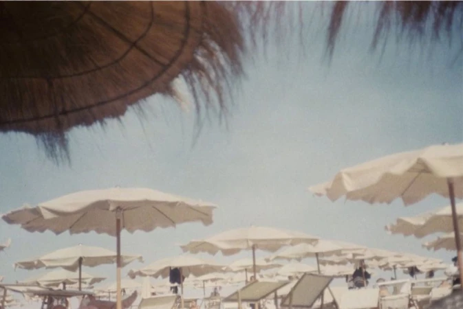 Beach umbrellas and chairs on a crowded beach under a sunny sky, creating a relaxing summer vacation scene.