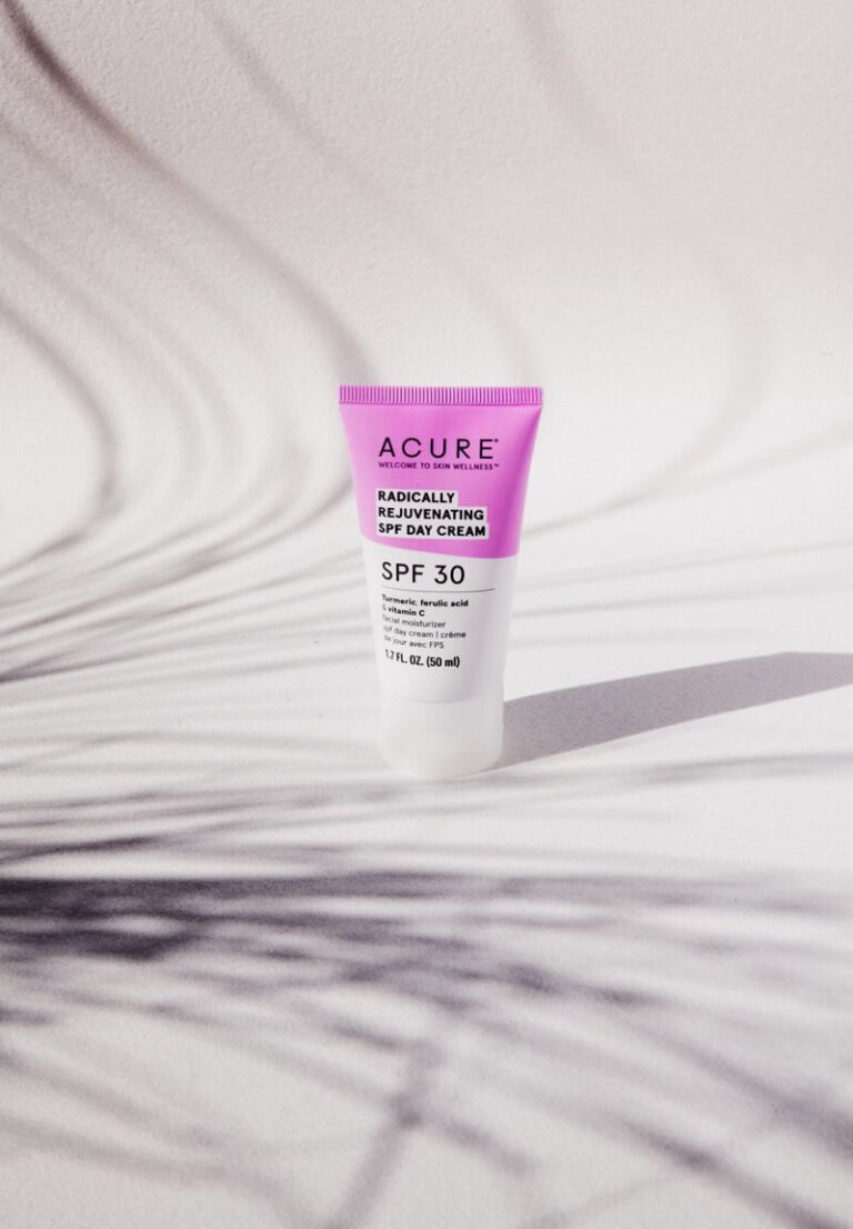 Acure SPF 30 day cream in pink and white tube on white backdrop with leaf shadows, ideal for beauty and skincare product shots.
