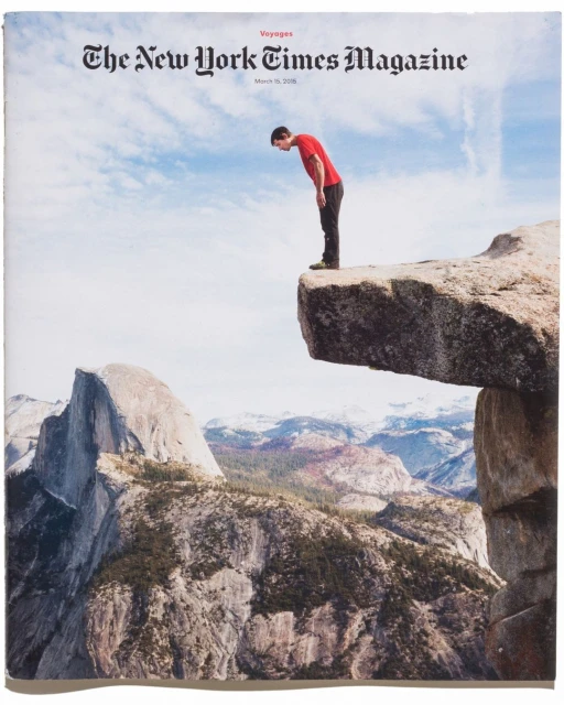 Magazine cover featuring a man standing on a rock cliff edge overlooking a mountain range against a partly cloudy sky, cover art.