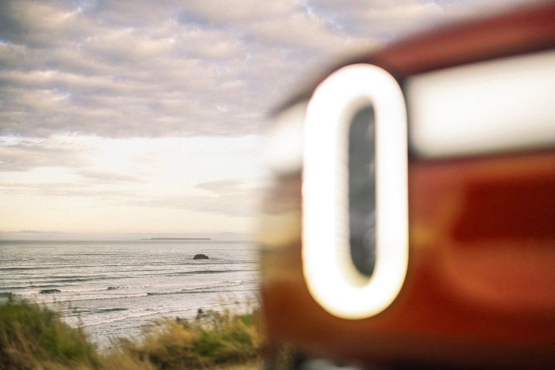 Abstract view of an ocean landscape with a blurred car detail featuring a white, glowing 'O' in the foreground, and the ocean horizon.