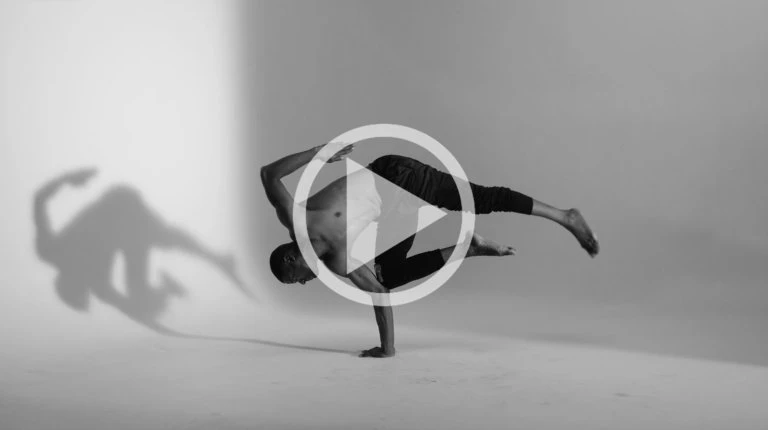Black and white photograph of a man breakdancing in a freeze pose against a plain light background by Peter Bohler.