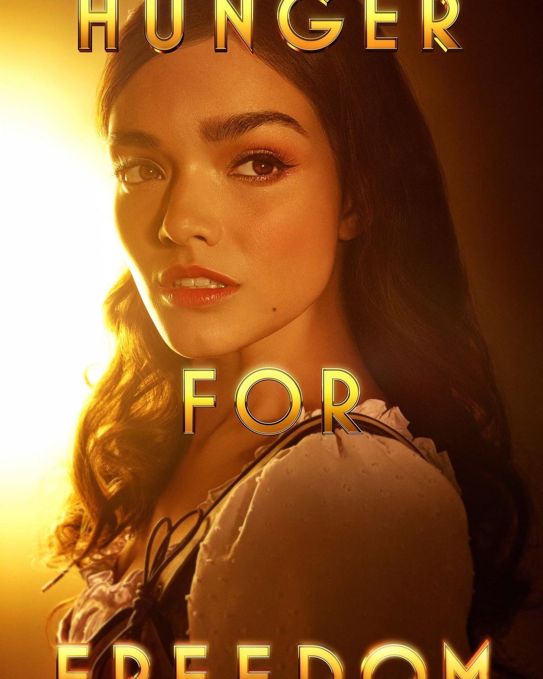 Portrait of a woman with long wavy brown hair wearing a white garment, against a golden-brown background and the words "Hunger for Freedom."