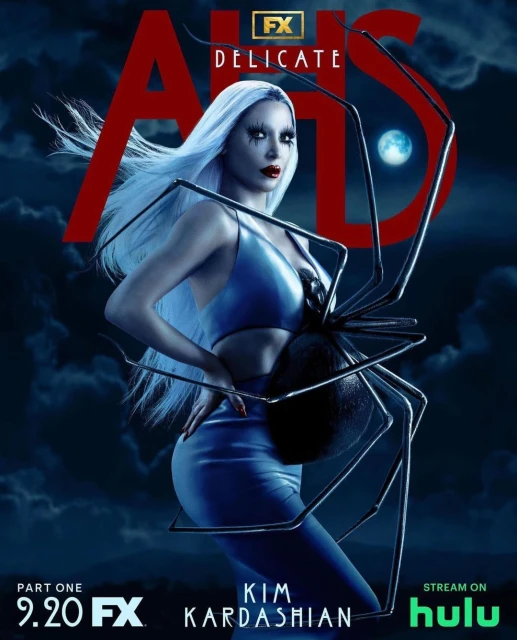Kim Kardashian stars in a promotional image for American Horror Story: Delicate, wearing a blue dress and holding a large spider.