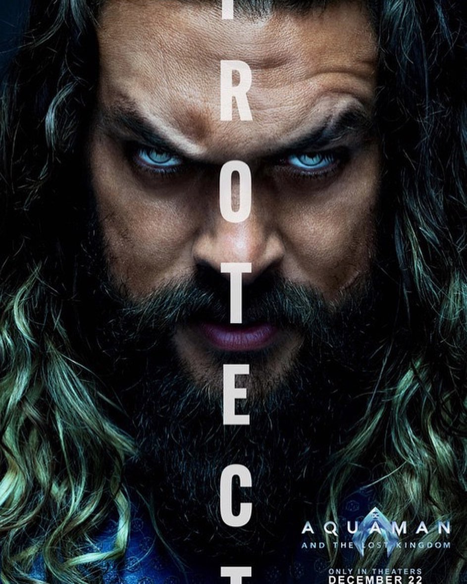 Close-up of Jason Momoa as Aquaman movie poster, featuring a stern expression with long hair, beard, and piercing blue eyes.