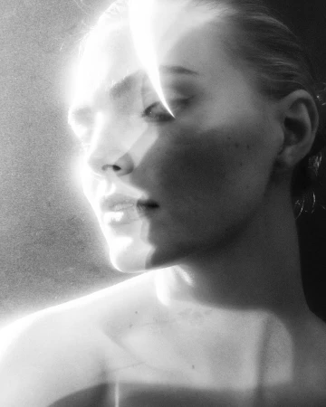 Close up monochrome portrait of a young woman with intense light refractions across her face, by Frank Ockenfels 3.