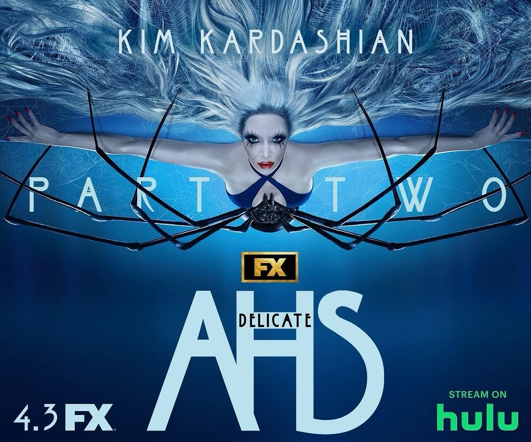 Kim Kardashian in American Horror Story: Delicate Part Two promotional image, wearing dark blue outfit and elaborate makeup, silver hair.