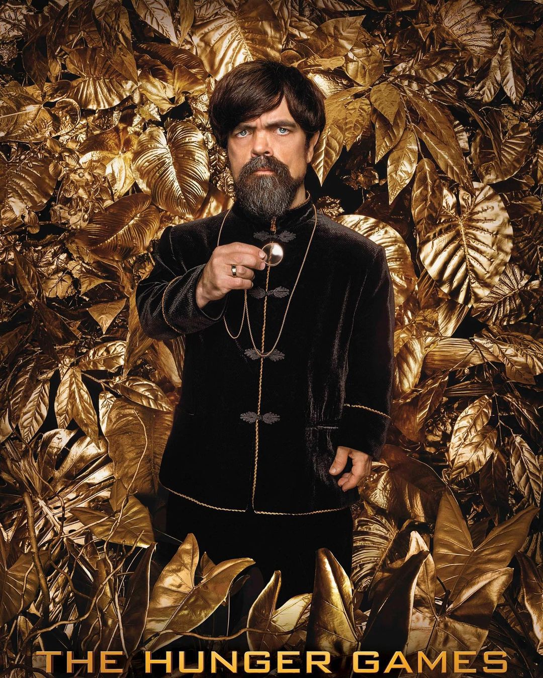 Portrait of Peter Dinklage as Tyrion Lannister, posing in a black velvet suit against a golden leaf background in a promotional still.