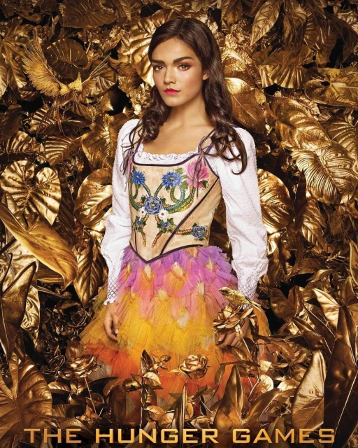 Portrait of female in decorative peasant blouse with feathery skirt and dark hair, posing against a gold floral background from 'The Hunger Games'.