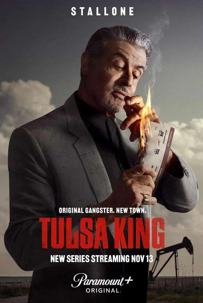 Sylvester Stallone in 'Tulsa King' series poster, wearing a suit, holding a burning ticket, set against a moody background with an oil rig.