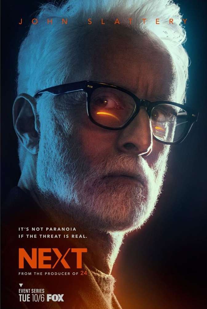 Headshot of John Slattery with a serious expression wearing glasses in front of a blurred background for a TV show called NEXT.