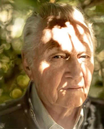 Close-up portrait of an elderly man with dappled sunlight filtering across his face, photographed by Frank Ockenfels 3.