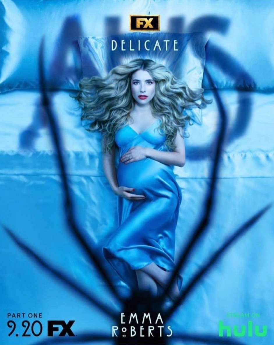 Promotional image for American Horror Story: Delicate featuring Emma Roberts in a blue dress, laying on a blue bed, with a spider overlay.