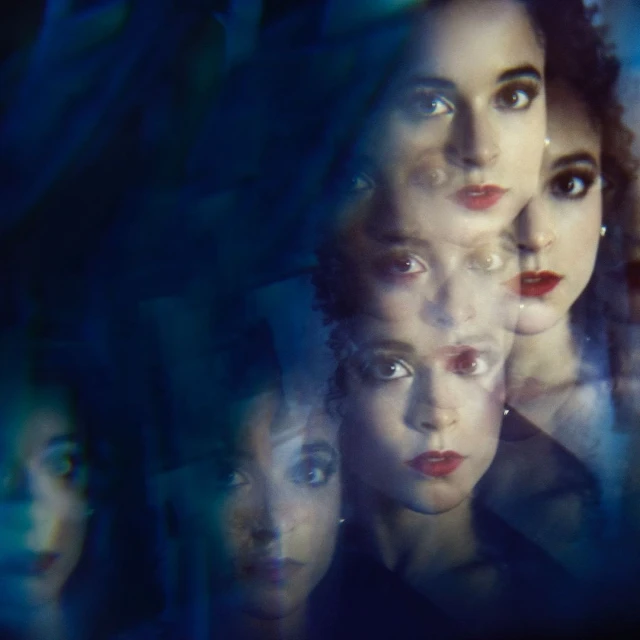 Multiple exposures of a woman with dark hair and red lipstick create a layered, surreal portrait against a deep blue background.