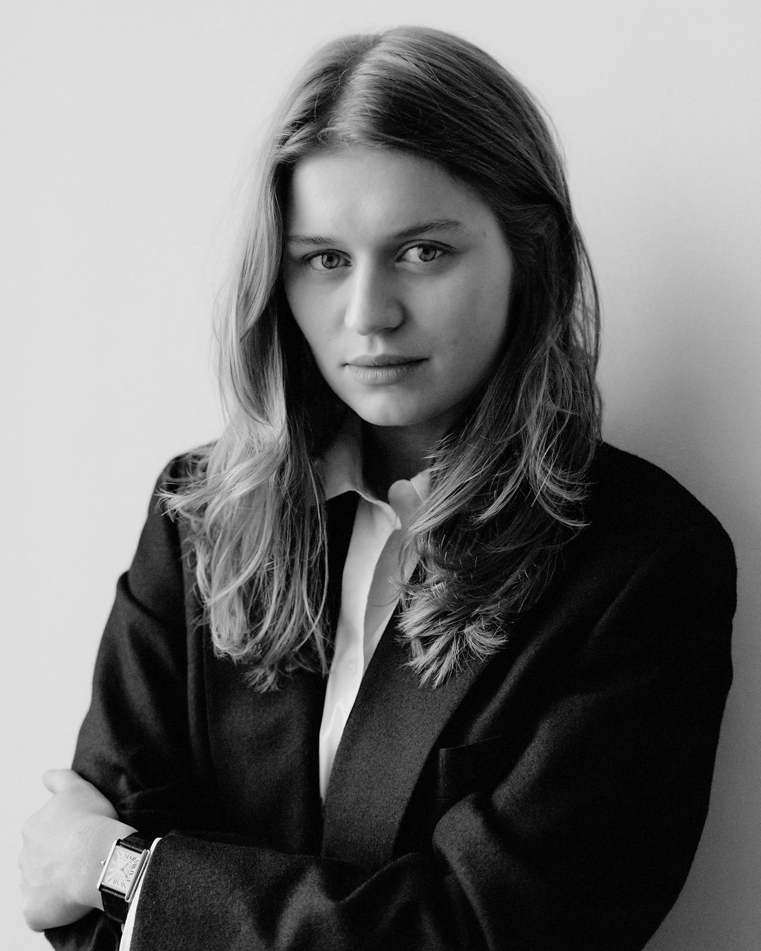 Black and white portrait of a woman in a dark blazer with arms crossed against a plain background