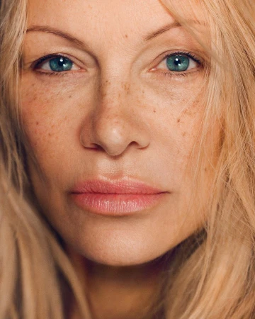 Close-up portrait of a woman with blonde hair, blue eyes, and freckles photographed by Heather Hazzan.