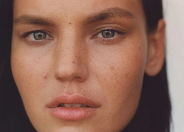 Close-up portrait of a woman with freckles and natural makeup photographed by Heather Hazzan.