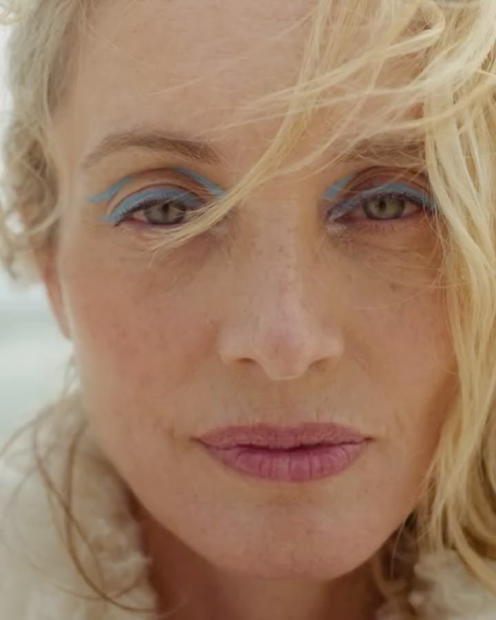 Close-up portrait of a woman with blonde hair, freckles, and light blue eye makeup by Heather Hazzan