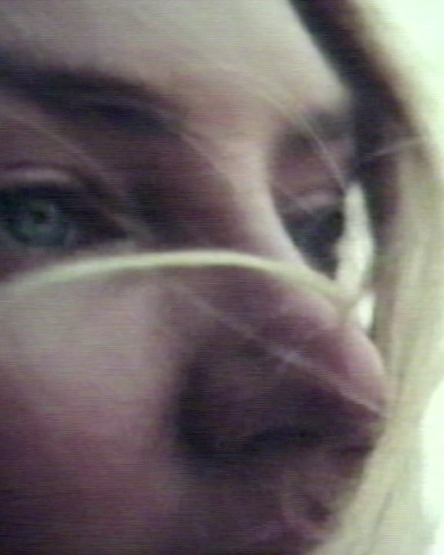 Close up macro portrait of a woman face with strands of blonde hair blowing across her eyes and nose.