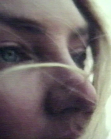 Close up macro portrait of a woman face with strands of blonde hair blowing across her eyes and nose.