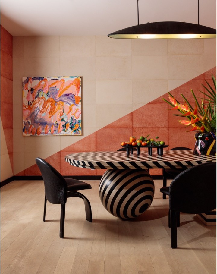 Modern dining room interior featuring black and white striped table, black chairs, abstract art, and unique lighting fixture.
