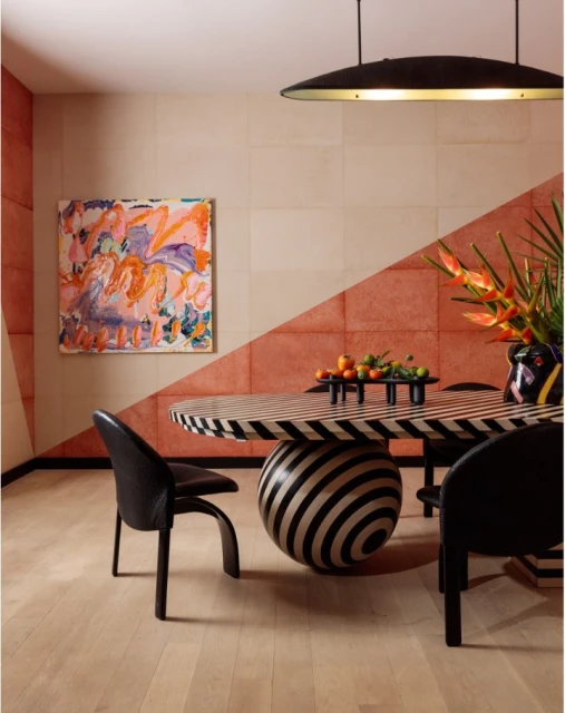 Modern dining room interior featuring black and white striped table, black chairs, abstract art, and unique lighting fixture.