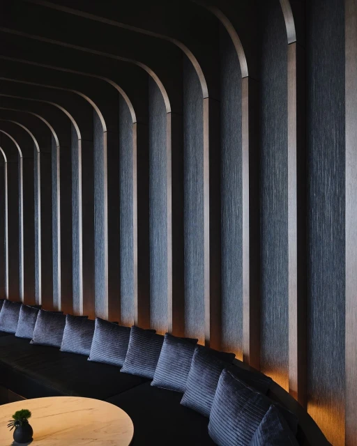 Interior design featuring a curved, dark wooden wall with integrated lighting, creating a modern and sophisticated architectural space.