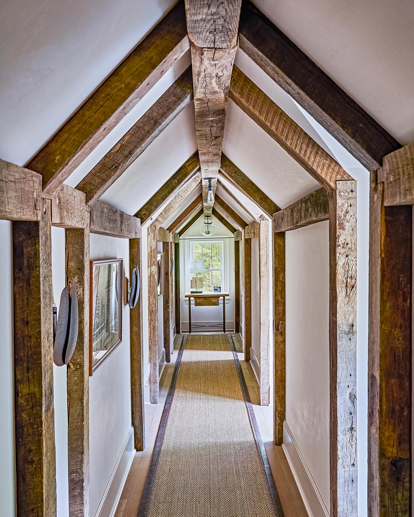 Hallway interior featuring reclaimed wood beams, white walls, and a woven rug. Interior design showcases rustic and modern elements.