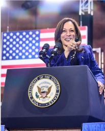 Kamala Harris speaking at a podium with the Presidential Seal in front of an American flag, photographed by Jen Rosenstein.