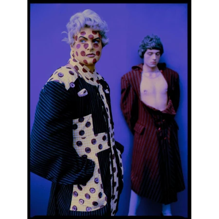 Two people in sculptural patterned garments against a solid blue backdrop photographed by Perry Ogden