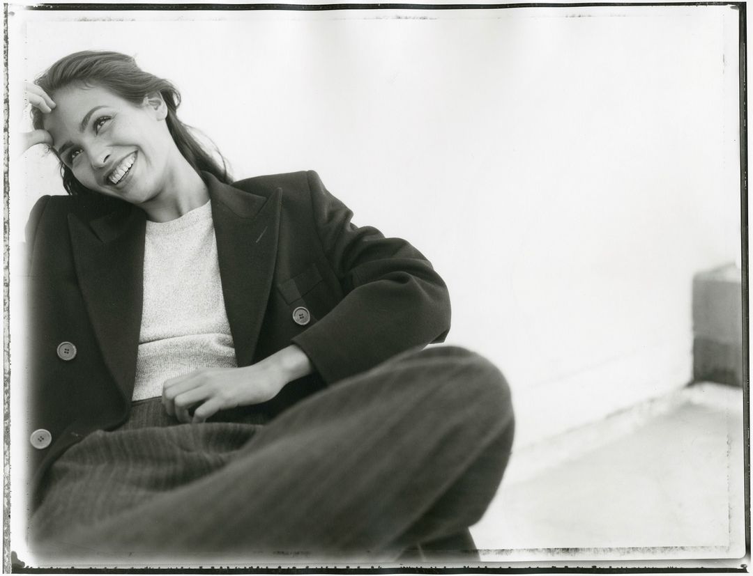 Monochrome portrait of smiling woman wearing a dark double-breasted blazer and knit top by photographer Perry Ogden.