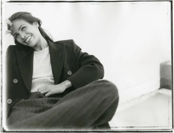 Monochrome portrait of smiling woman wearing a dark double-breasted blazer and knit top by photographer Perry Ogden.