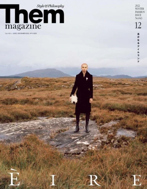 Them magazine cover featuring a person in a black coat standing in a field, with text overlay and mountain backdrop.