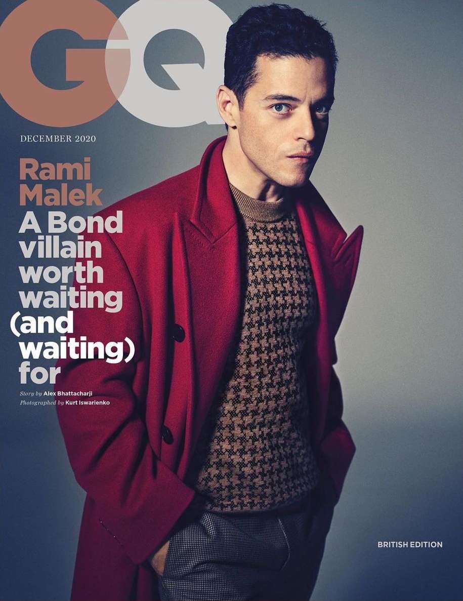 Rami Malek on GQ cover, December 2020 issue. He is wearing a brown patterned sweater, red coat, and grey pants.