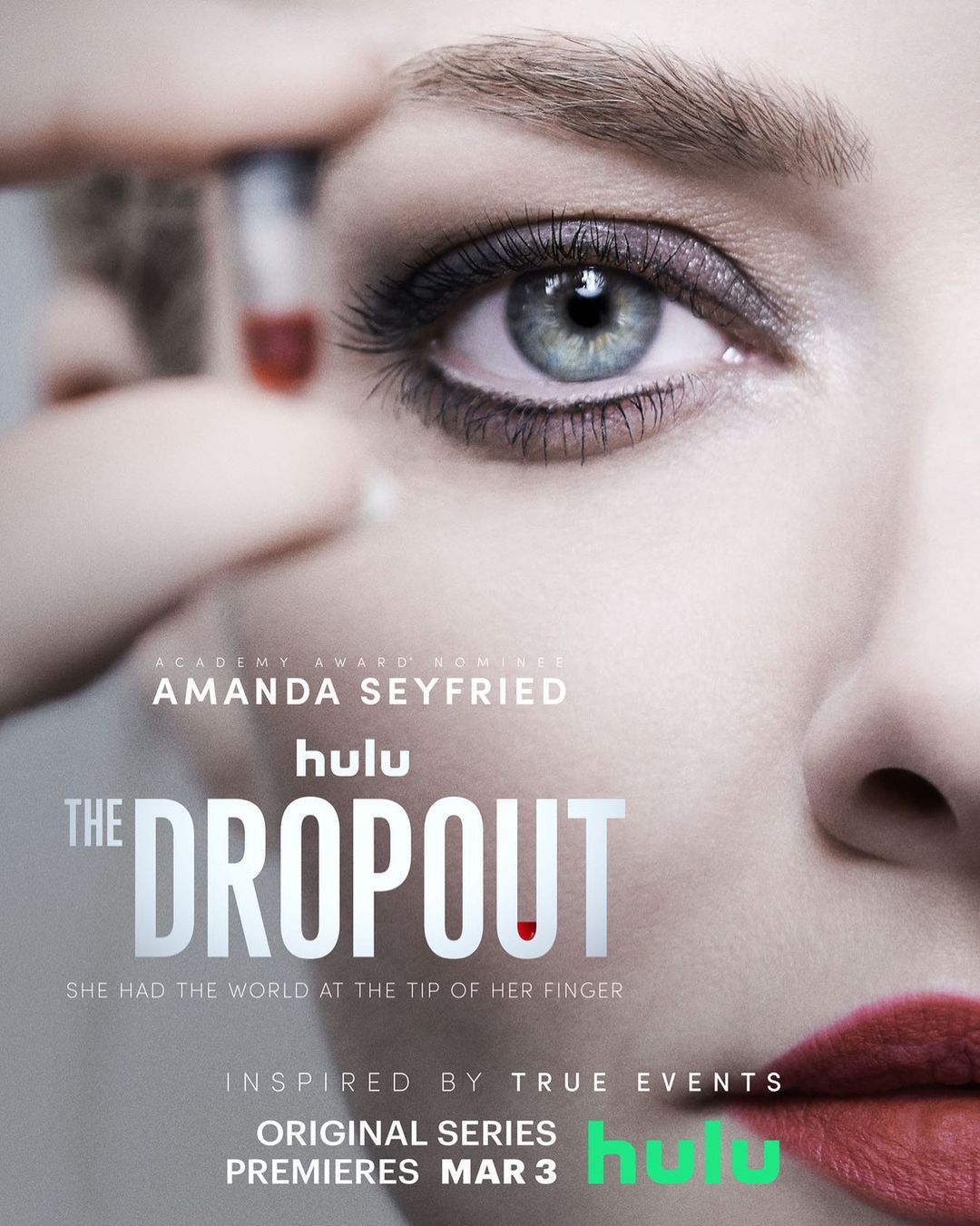 Close-up of Amanda Seyfried's face from "The Dropout" promo with a vial of blood, emphasizing her eye makeup and red lipstick.