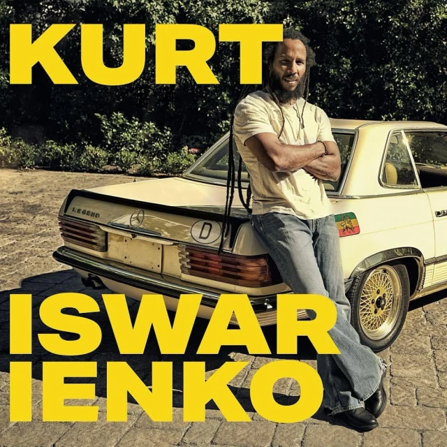 Adult male stands with arms crossed next to a vintage cream-colored Mercedes Benz in an outdoor setting with bright yellow text.