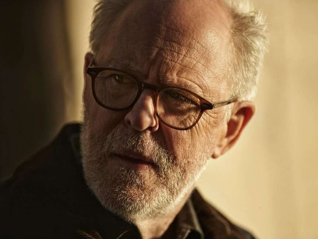 Close-up portrait of an older man with glasses and a grey beard photographed by Kurt Iswarienko.