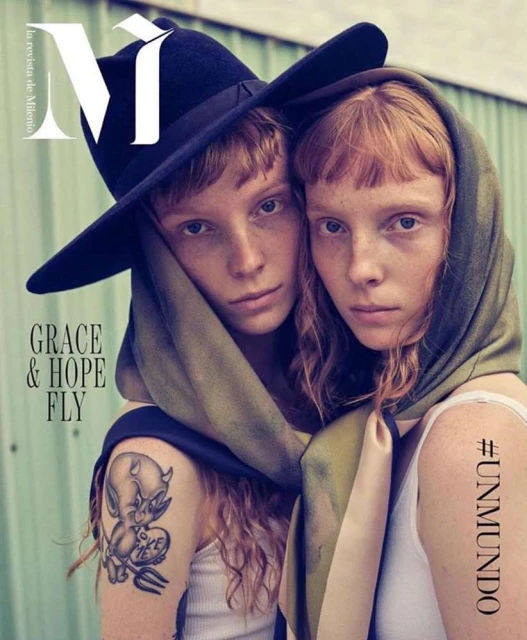 Fashion magazine cover featuring two adult female models with freckles, one in a black hat, and both draped in a scarf.