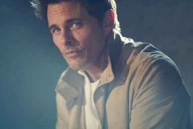 Portrait of actor James Marsden wearing a beige jacket and white t-shirt against a neutral background, photographed by Kurt Iswarienko.