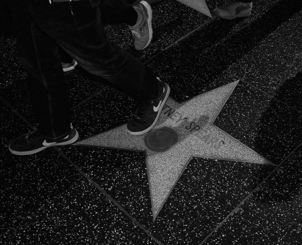 Hollywood Walk of Fame star honoring Britney Spears, captured from a high angle with pedestrians walking by on the speckled pavement.