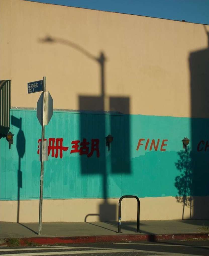 A street view of a building with a light teal painted band, red painted Chinese characters, and the word FINE on the building's facade.