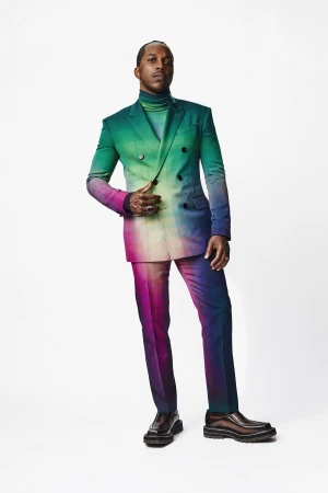 Full body studio shot of an adult male in a colorful suit. The jacket is a double breasted blazer with pants and leather shoes.