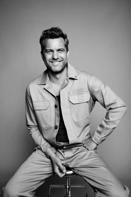 Leigh Keily portrait. Man with short brown hair, wearing a black collared shirt in a photo studio with gray background.