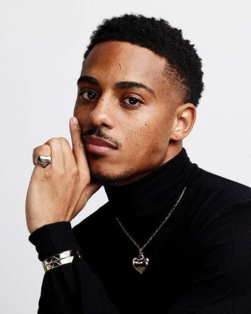 Close-up portrait of a Black man wearing a black turtleneck and silver heart ring, photographed by Leigh Keily